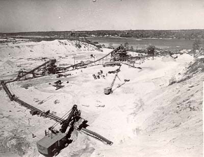 From bottom: sand is loaded onto conveyor belt, then crushed and screened, goes into washing plant (top, middle), deposited in raw storage, delivered under tunnel to barges for trip to NYC.