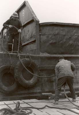 Santo Bassi tying rope on empty barge, preparing it for loading, Plant 1, Hempstead Harbor, Colonial Sand Mining Company