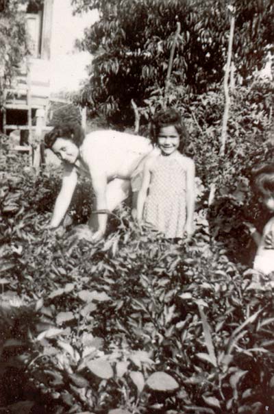 Nancy Deriu Palen (center) in middle of garden at sandbank housing, 1950s